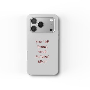 Puede incluir: Funda de teléfono gris claro con un módulo de cámara en la parte superior. La funda tiene el texto "YOU'RE DOING YOUR FUCKING BEST" en rojo oscuro.