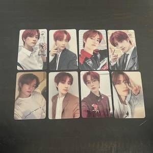 May include: Eight rectangular photo cards featuring a person with red hair in various poses and outfits. The cards are arranged in two rows of four on a dark surface. The outfits include a white shirt, a blazer, and a jacket.