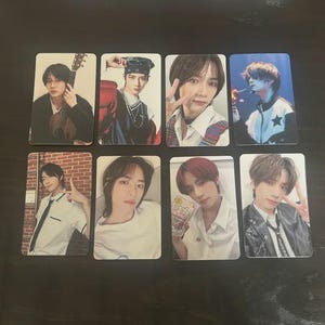 May include: A collection of eight photo cards featuring images of a male musical artist. The cards display various poses, including holding a guitar, making a peace sign, and wearing different outfits. The cards are rectangular with rounded corners.