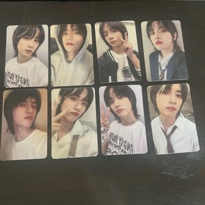 May include: A collection of eight rectangular photo cards featuring a young person with dark hair and various outfits. The cards display different poses and expressions, with some including text on the clothing.