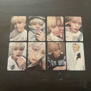 May include: Eight rectangular photo cards featuring a young person with blonde hair. The cards show different poses and expressions, with some featuring the person in a hoodie or with small decorative stickers on their face.
