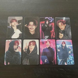 May include: A collection of eight rectangular photo cards featuring a person with red hair in various poses. The cards show the person in different outfits, including hoodies and jackets, with some holding a microphone or phone.