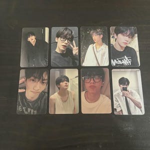 May include: A collection of eight rectangular photo cards featuring images of a person in various poses. The cards display different outfits and expressions, with some wearing glasses or holding a phone.