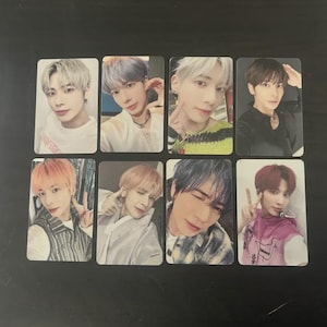 May include: Eight rectangular photo cards featuring different young men. Each card displays a head and shoulders portrait of a man with various hairstyles and clothing. The cards are arranged in two rows of four on a dark surface.
