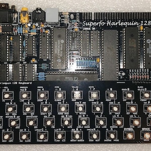 Puede incluir: Una placa de circuito de teclado Superfo Harlequin 128 negra con numerosos componentes electrónicos, incluyendo chips, resistencias y conectores. La sección del teclado presenta teclas blancas con varios símbolos y texto. El texto "Superfo Harlequin 128" es visible.