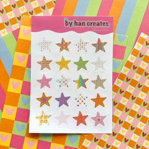 May include: A sheet of colorful star stickers with various patterns, including stripes, polka dots, and plaid. The stickers are on a white card with the text "by han creates Whimsy Stars". The background features patterned paper with hearts and stripes.