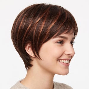May include: A short, layered wig featuring a dark brown base color with subtle copper-toned highlights throughout. The hair is styled in a textured, piecey cut with soft bangs that frame the face, worn over a beige knit sweater.