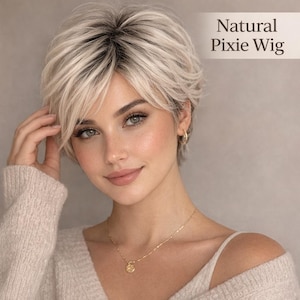 Könnte beinhalten: Ein kurzer, gestufter Pixie-Wig mit einer Mischung aus blonden und dunklen Ansätzen. Die Perücke hat ein natürliches Aussehen und ist mit weichen Wellen gestylt. Der Text "Natural Pixie Wig" wird angezeigt.