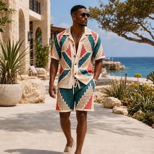 Può includere: Un completo composto da una camicia a maniche corte con bottoni e pantaloncini abbinati, caratterizzato da un motivo geometrico all'uncinetto nei colori crema, verde acqua e corallo. La camicia ha un colletto classico e i pantaloncini un cordino.