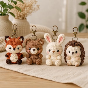 Può includere: Quattro portachiavi a forma di animale realizzati all'uncinetto: una volpe, un orso, un coniglio e un riccio. Ogni figura è creata con filato nei toni dell'arancione, marrone e crema, con piccoli occhi neri, guance rosa e un moschettone in bronzo.