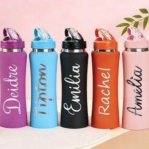Puede incluir: Cinco botellas de agua personalizadas en morado, azul, negro, naranja y rosa. Cada botella tiene un nombre plateado impreso verticalmente. Las botellas tienen una tapa abatible y una base de acero inoxidable. Los nombres son Deidre, Tipton, Emilia, Rachel y Amelia.