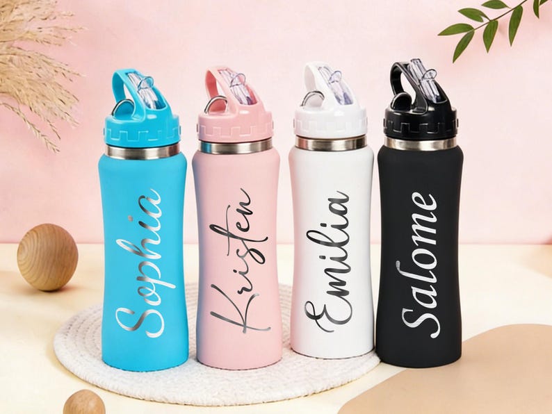 Puede incluir: Cuatro botellas de agua personalizadas en azul, rosa, blanco y negro. Cada botella tiene un nombre plateado: Sophia, Kristen, Emilia y Salome. Las botellas tienen un borde plateado y una tapa abatible con pajita.