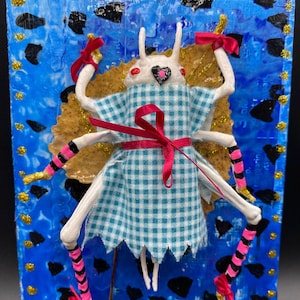 Arte di insetti a tecnica mista: personaggio di fiaba riciclato, mashup del mago di Oz, vestito a quadretti, gambe da strega