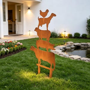 Puede incluir: Escultura de jardín de metal oxidado que representa una pila de animales de granja: una vaca, un cerdo, una oveja, una cabra y una gallina. La escultura es de metal envejecido y se alza sobre un césped, añadiendo un toque encantador.