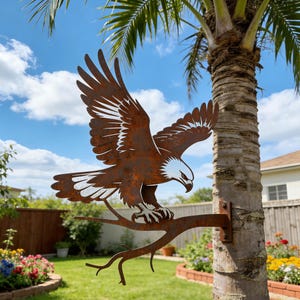 May include: A metal sculpture of an eagle perched on a branch, with outstretched wings. The eagle has a rusty brown finish with white and brown details. The sculpture is mounted on a tree trunk in a garden setting.