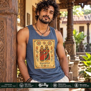 May include: A heather blue tank top featuring a rectangular graphic print of two figures in traditional attire with floral borders and Sinhala script text. The design includes three circular floral motifs above the figures and orange flower stems.