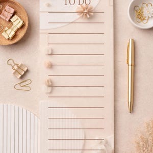 Op de afbeelding: Een beige To Do-notitieblok met horizontale lijnen en de tekst "TO DO". Een gouden pen, paperclips en een kopje koffie zijn ook zichtbaar. Decoratieve elementen zijn inbegrepen.