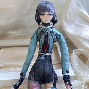 May include: A plush doll featuring a character with short grey hair and blue eyes. The doll wears a light blue long-sleeved top with dark grey accents and a black tie, paired with dark grey shorts. The fabric has a printed design.