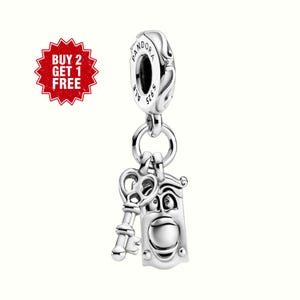 May include: A silver charm with a key and a door knocker design. The charm is suspended from a larger, ornate silver bead. The door knocker has a face design. The charm is marked with "S925 ALE" and "PANDORA".