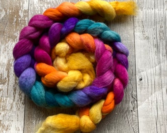 Könnte beinhalten: Ein geflochtenes Bündel aus buntem Garn in den Farben Gelb, Orange, Rosa, Lila, Türkis und Blau. Das Garn ist spiralförmig angeordnet.