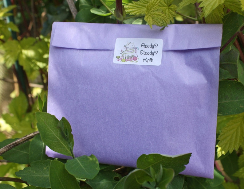 May include: A lavender-colored tissue paper envelope with a white sticker that says "Ready? Steady? Knit!"