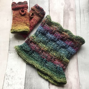 May include: A colorful knitted fingerless glove set with a matching cowl. The gloves and cowl are made with a variety of shades of green, blue, red, and yellow yarn. The cowl has a scalloped edge.