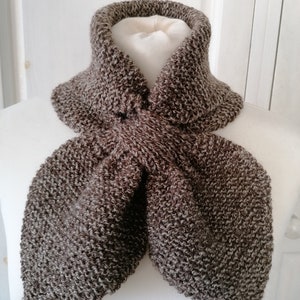 May include: A brown and gray knitted scarf displayed on a white mannequin. The scarf is made of a textured yarn and has a folded design. The scarf is designed to be worn around the neck.