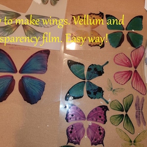 以下が含まれることがあります： 青、ピンク、緑、紫など、さまざまな色の蝶の羽のデザインが透明なシートに並んでいます。「How to make wings. Vellum and transparency film. Easy way!」というテキストがクラフトプロジェクトに表示されています。