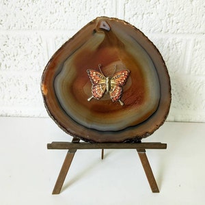 May include: A brown agate slice with a painted butterfly on a small wooden easel.