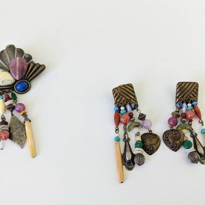 May include: A set of colourful, bohemian-style jewellery featuring a brooch and a pair of earrings. The brooch has a fan-shaped design with a variety of stones and beads, while the earrings have a similar design with heart-shaped pendants.