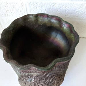May include: A dark green and brown ceramic planter with a wavy rim. The planter has a textured surface and a slightly iridescent finish.