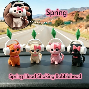 Puede incluir: Cuatro figuras de gato con cabeza oscilante en naranja, crema, rosa y negro. Cada gato lleva auriculares blancos y un lazo rosa. Las figuras tienen acentos verdes en forma de diamante. Se muestran las palabras "Spring" y "Spring Head Shaking Bobblehead".