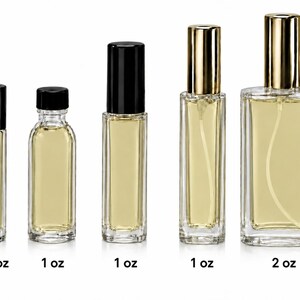 May include: Five clear glass bottles filled with pale yellow liquid. From left to right: a 1/3 oz roller bottle with a black cap, a 1 oz round bottle with a black cap, a 1 oz rectangular roller bottle with a black cap, a 1 oz rectangular spray bottle with a gold cap, and a 2 oz rectangular spray bottle with a gold cap.