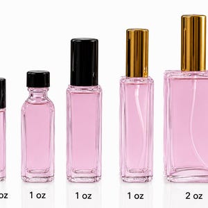 May include: Five clear glass bottles filled with pink liquid, arranged by size from 1/3 oz to 2 oz. The first three have black caps, while the last two feature gold spray nozzles. Each bottle is labeled with its capacity in ounces below it.