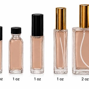May include: Five clear glass bottles filled with a light beige liquid. From left to right: a 1/3 oz roller bottle with a black cap, a 1 oz bottle with a black screw cap, a 1 oz roller bottle with a black cap, and two spray bottles with gold caps.