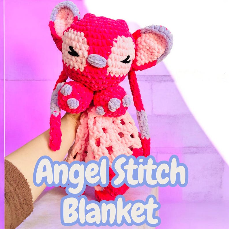 May include: A handmade, plush, pink and white Angel Stitch blanket. The crochet blanket features a character with large ears, closed eyes, and a patterned design. The text "Angel Stitch Blanket" is displayed in a blue font.