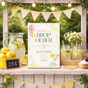 May include: A festive outdoor scene with a birthday invitation, lemonade, and decorations. The invitation reads "Valentina is a DROP OLDER 30." Lemonade is served in a pitcher, mason jars, and a yellow bucket. Yellow and white pennant banners and string lights complete the party setting.