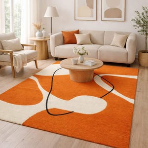 May include: An orange and white abstract patterned area rug. The rug features large, organic shapes in white against a vibrant orange background, with a black line accent. The rug is placed in a living room setting.