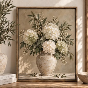 May include: A framed wall art print depicting a bouquet of white hydrangea flowers and green foliage arranged in a textured, beige ceramic vase. The painting features a neutral, earthy colour palette with soft lighting and visible brushstroke textures.