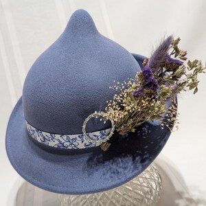 Sombrero único de lana azul adornado con un broche vintage y flores secas.