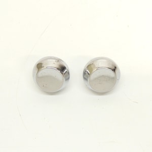 May include: Two circular, dome-shaped cabinet knobs with a polished, reflective chrome finish. Each knob features a smooth, rounded top surface that tapers slightly toward the base, presenting a clean, metallic appearance with no additional hardware.