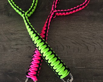 Peut inclure: Deux laisses en paracorde avec du paracorde noir et vert fluo et noir et rose fluo. Les laisses ont des clips pivotants argentés.