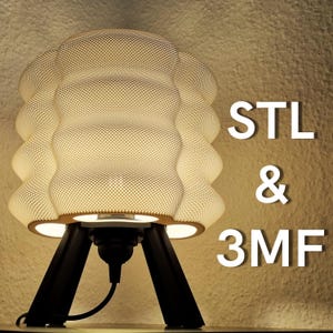 Puede incluir: Una lámpara moderna de color crema con una pantalla texturizada y punteada, sobre una base de trípode negra. El texto "STL & 3MF" se muestra en blanco. La lámpara está encendida, emitiendo un brillo cálido. Diseño moderno y elegante.
