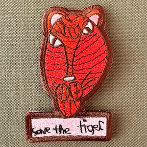 May include: Embroidered patch with a tiger face in red, orange, and brown. The patch has the text "Save the tiger" in black script on a rectangular banner. The patch has a brown border. Ideal for clothing or accessories.