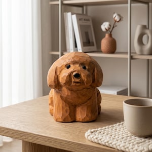 May include: A wooden sculpture of a dog, carved with visible wood grain. The dog is light brown and sits on a wooden table. The sculpture has a detailed face and a fluffy appearance. The background includes a shelf with books and decorative items.