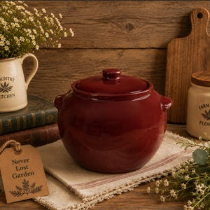 May include: A rustic kitchen scene featuring a burgundy ceramic pot with a lid, a cream-colored pitcher with "Country Kitchen" text, and a jar labeled "Farm Fresh Flowers." A wooden cutting board and a tag that says "Never Lost Garden" are also present.