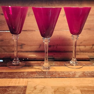 May include: A set of three ceramic mugs with a speckled, cream-colored glaze. Each mug features a different hand-painted floral design in shades of blue, green, and yellow. The mugs have a simple, rounded shape and a comfortable handle.