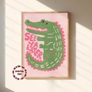 Op de afbeelding: Een kruissteekpatroon met een groene alligator op een lichtroze achtergrond met de tekst SEE YA LATER in het roze. Het ontwerp bevat een cirkelvormige stempel in de hoek met de tekst 81 X 115 A5 DIGITAL PDF, die de afmetingen aangeeft.