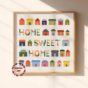 May include: A framed cross-stitch design with the words "HOME SWEET HOME" and rows of colorful houses. The houses are in shades of red, yellow, blue, and green. The text is also in a variety of colors. The words "DIGITAL PDF" are in the lower left corner.