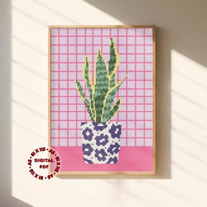 May include: A cross-stitch pattern featuring a green and yellow snake plant in a purple and white leopard print pot, set against a pink grid background. The text 81 X 115, A5, DIGITAL PDF is printed in a circular arrangement in the bottom left corner.